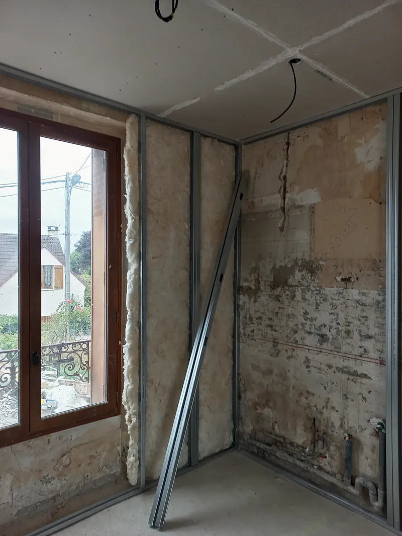 Doublage en cours : ossature métallique contre le mur ancien.