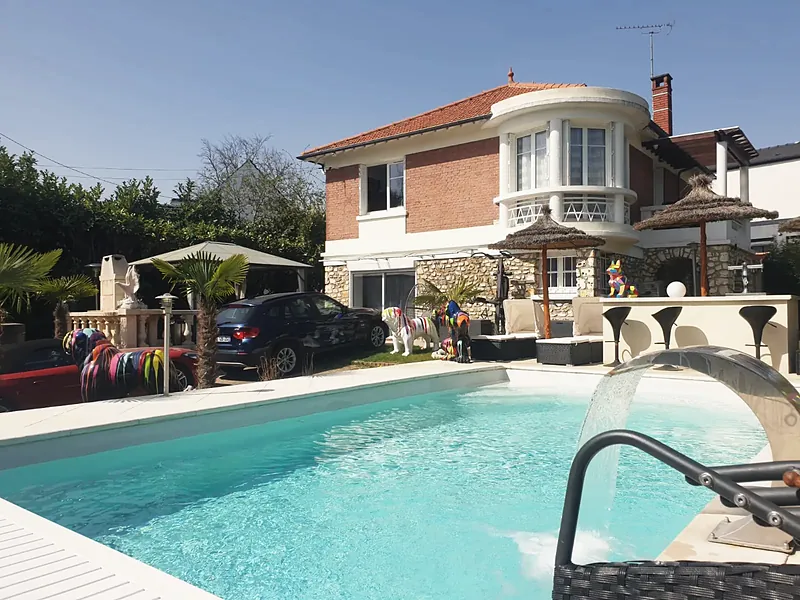 La villa avant travaux : étage en brique rouge avec bow-window arrondi et toiture à quatre pans en tuiles rouges, piscine au premier plan.